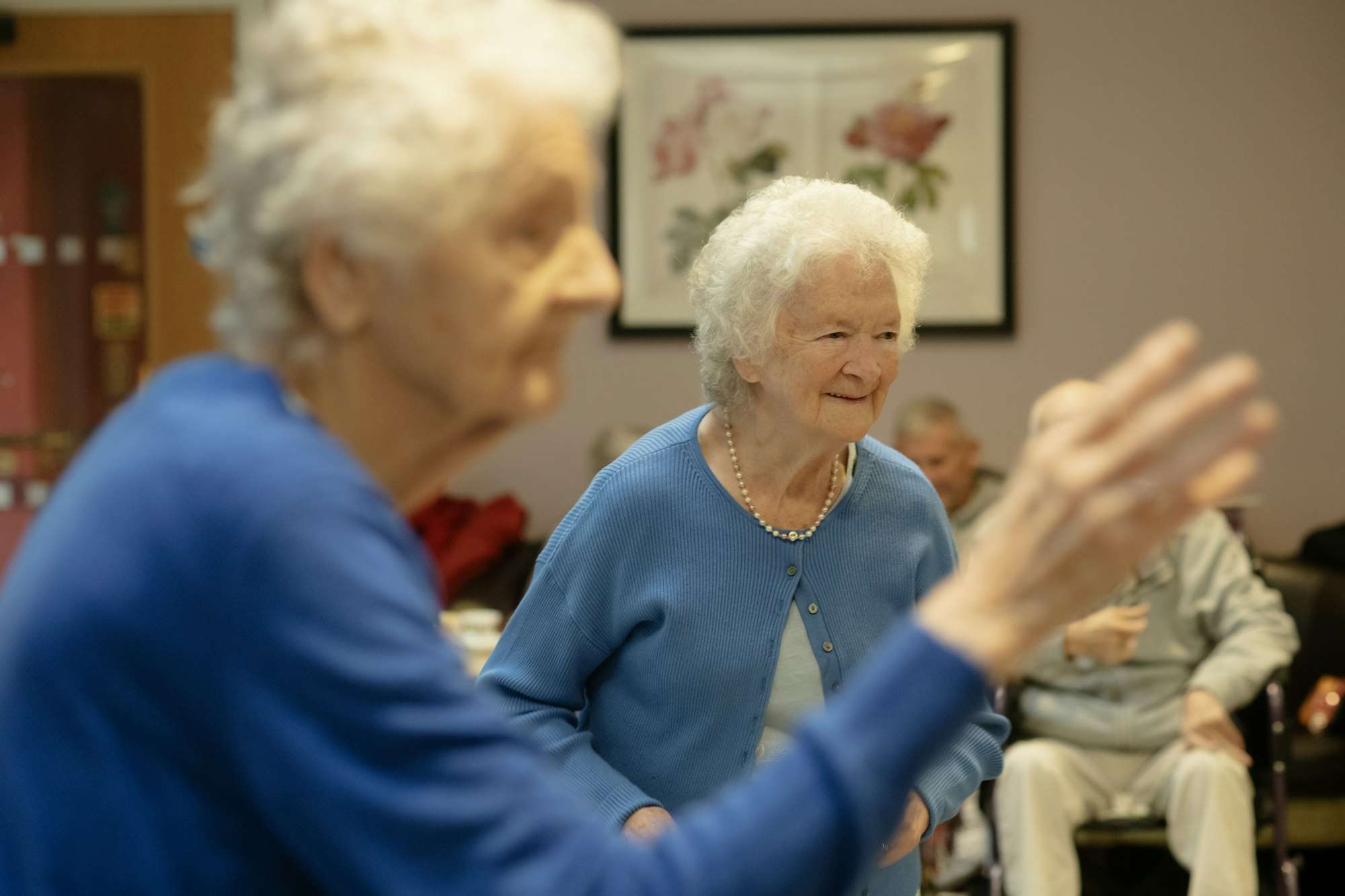 Deux femmes âgées, souriantes, participent à une activité dans une salle commune