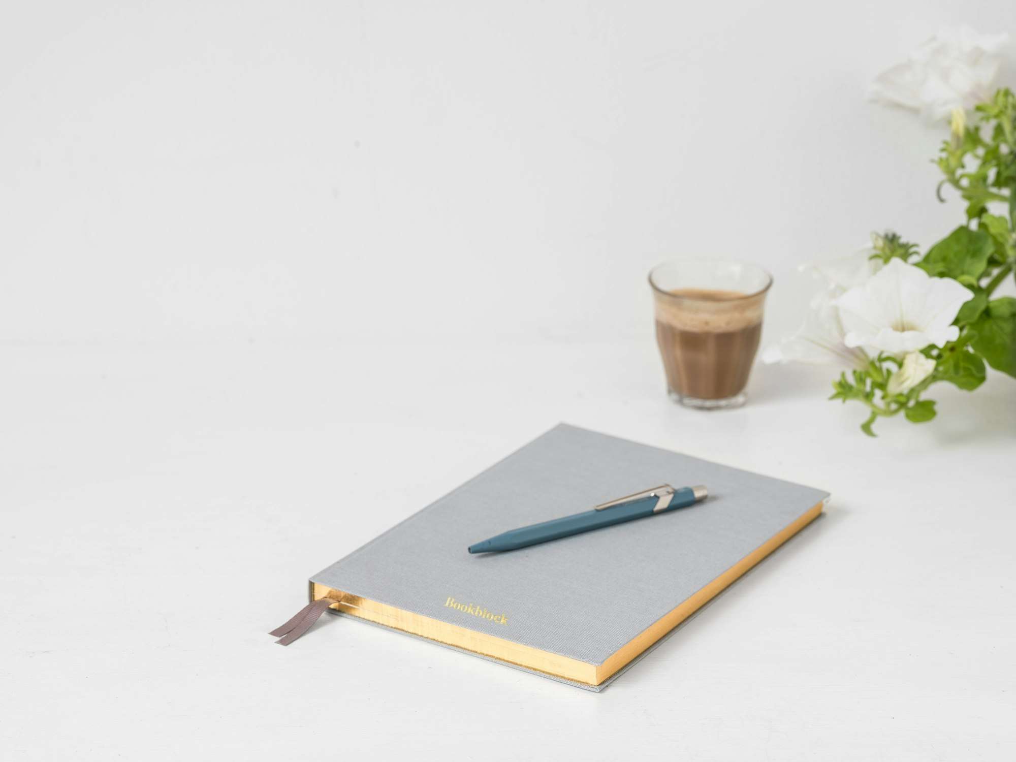 Carnet gris et stylo posés à côté d’un verre de café