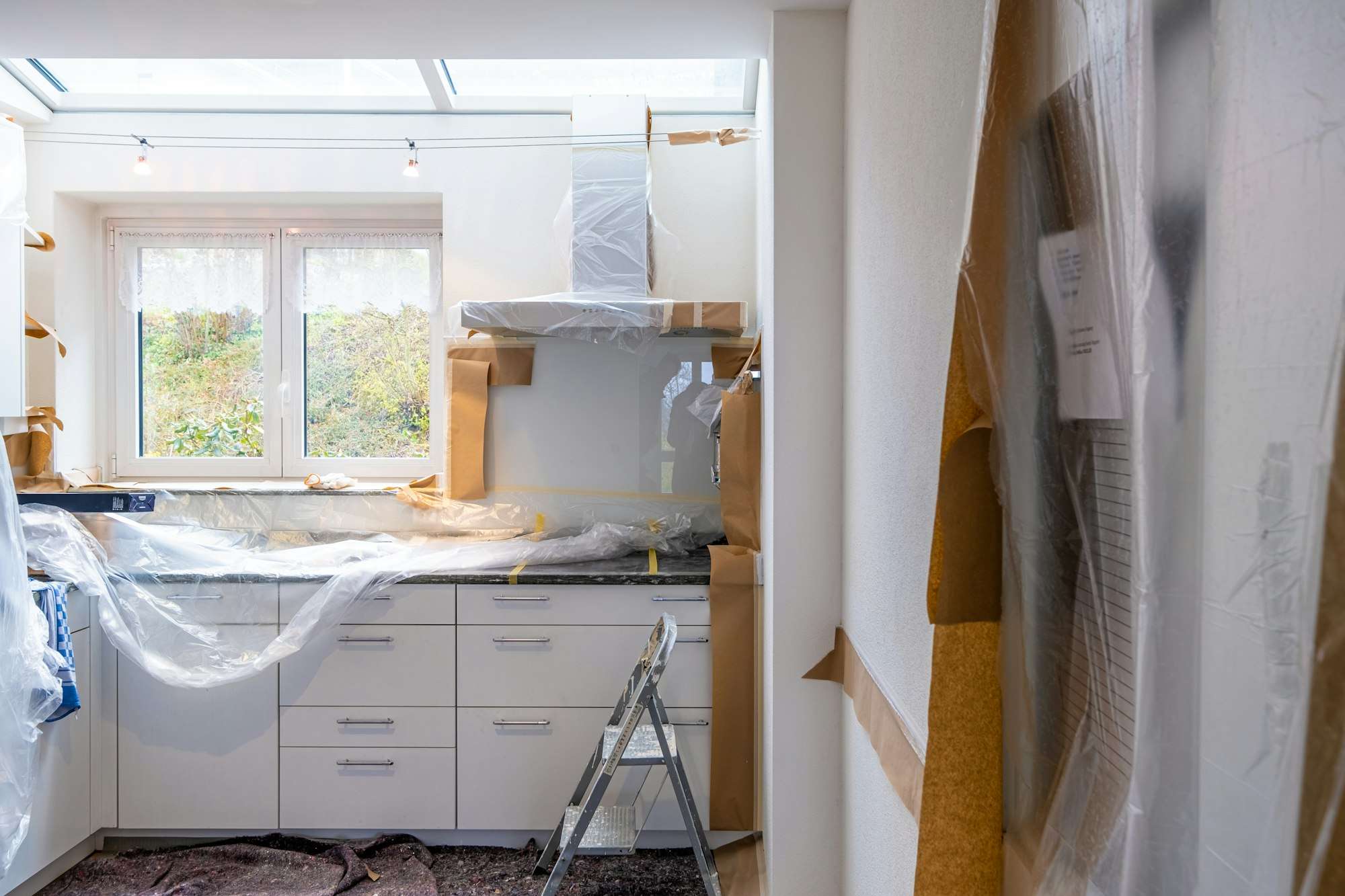 Cuisine en travaux, meubles blancs protégés sous bâche plastique