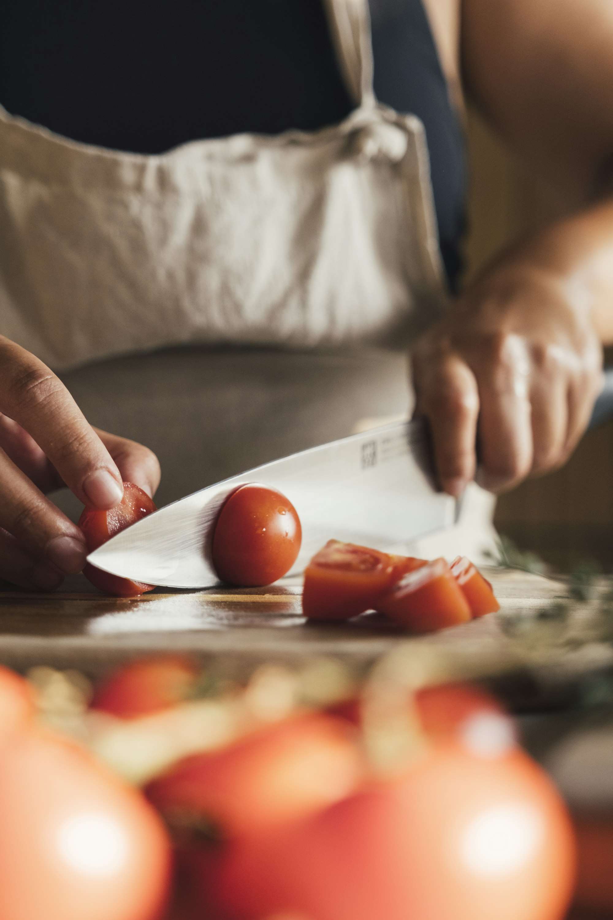 Mains coupant des tomates sur une planche, en cuisine