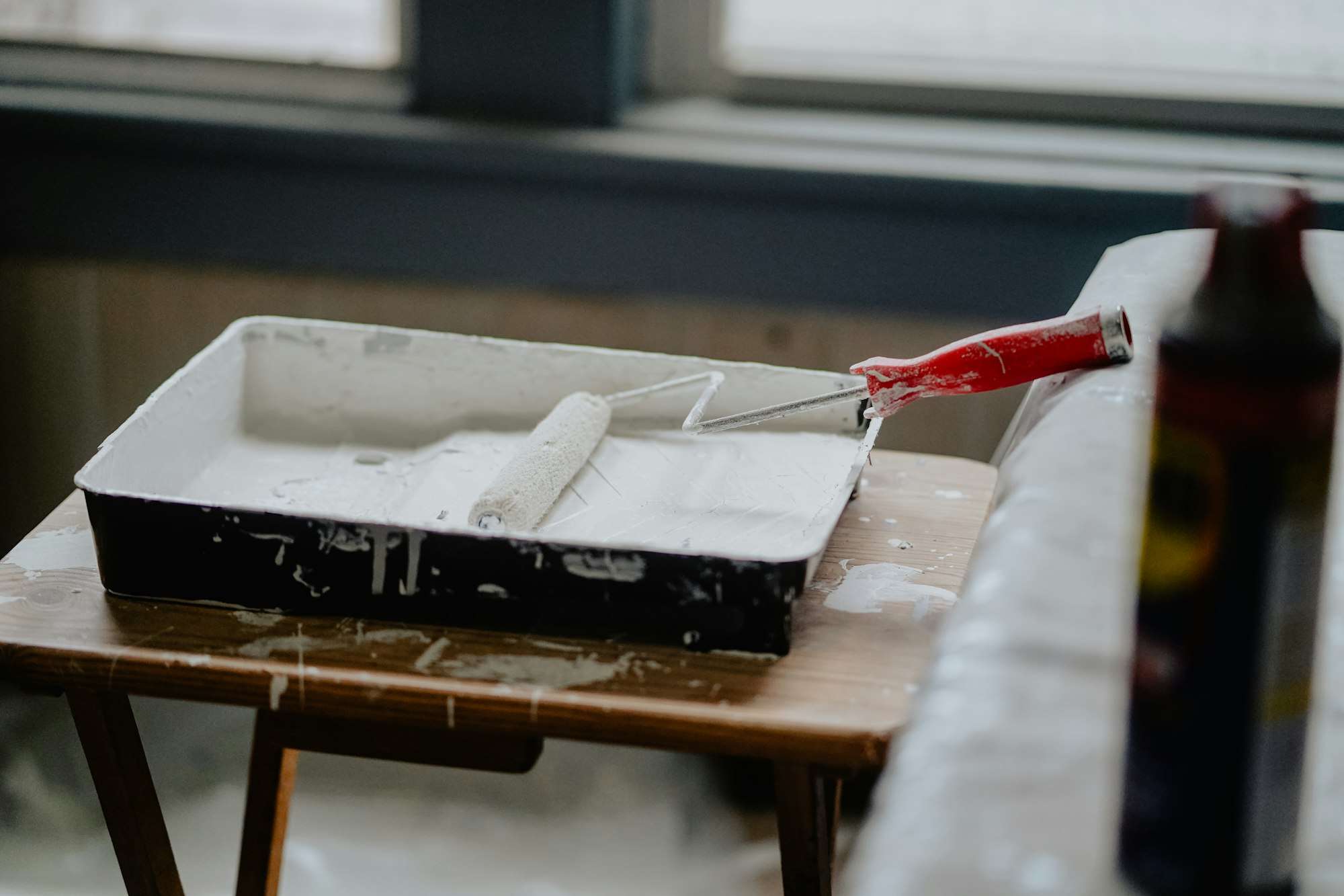 Rouleau de peinture posé dans un bac de peinture blanche