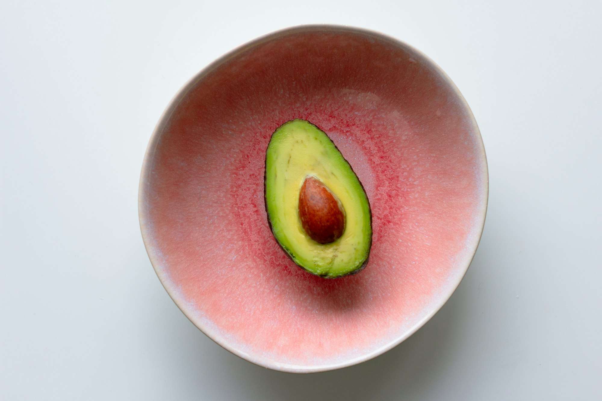 Demi-avocat posé dans un bol rose, vu de dessus