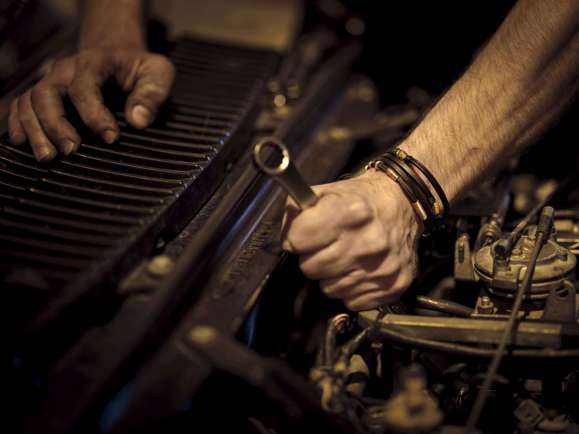 Mains réglant un carburateur dans un compartiment moteur