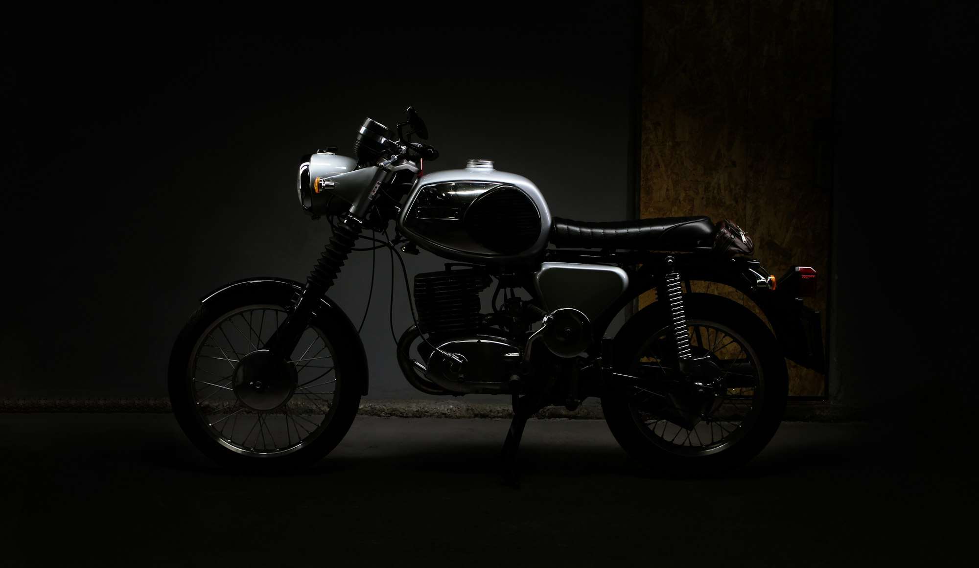 Moto ancienne de profil dans la pénombre d’un atelier