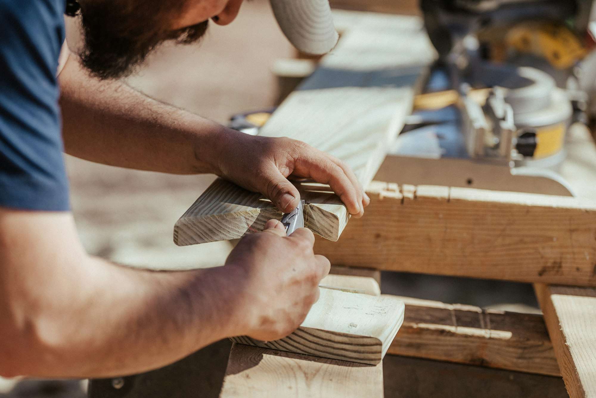 Mains façonnant une pièce de bois à l’établi