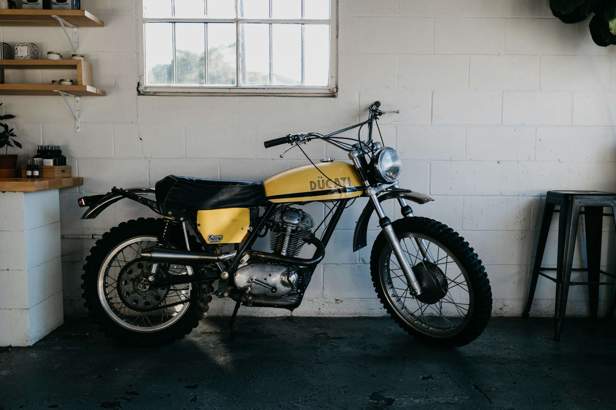 Moto tout-terrain ancienne jaune et noire dans un atelier blanc