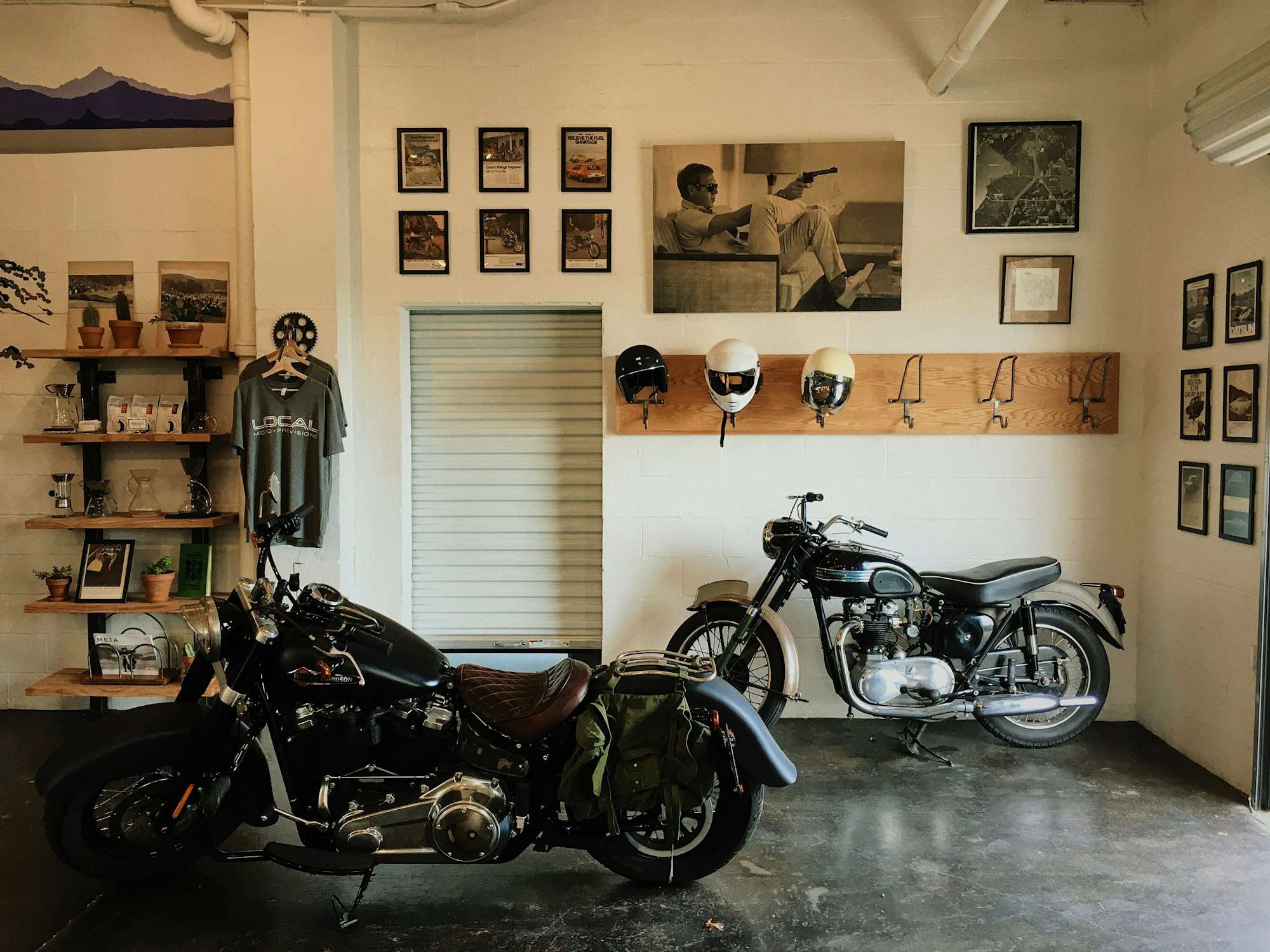 Deux motos anciennes garées dans un local aux murs couverts de cadres