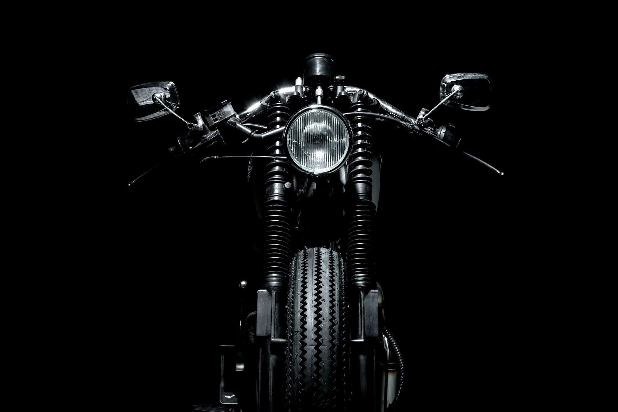 Moto café racer vue de face sur fond noir